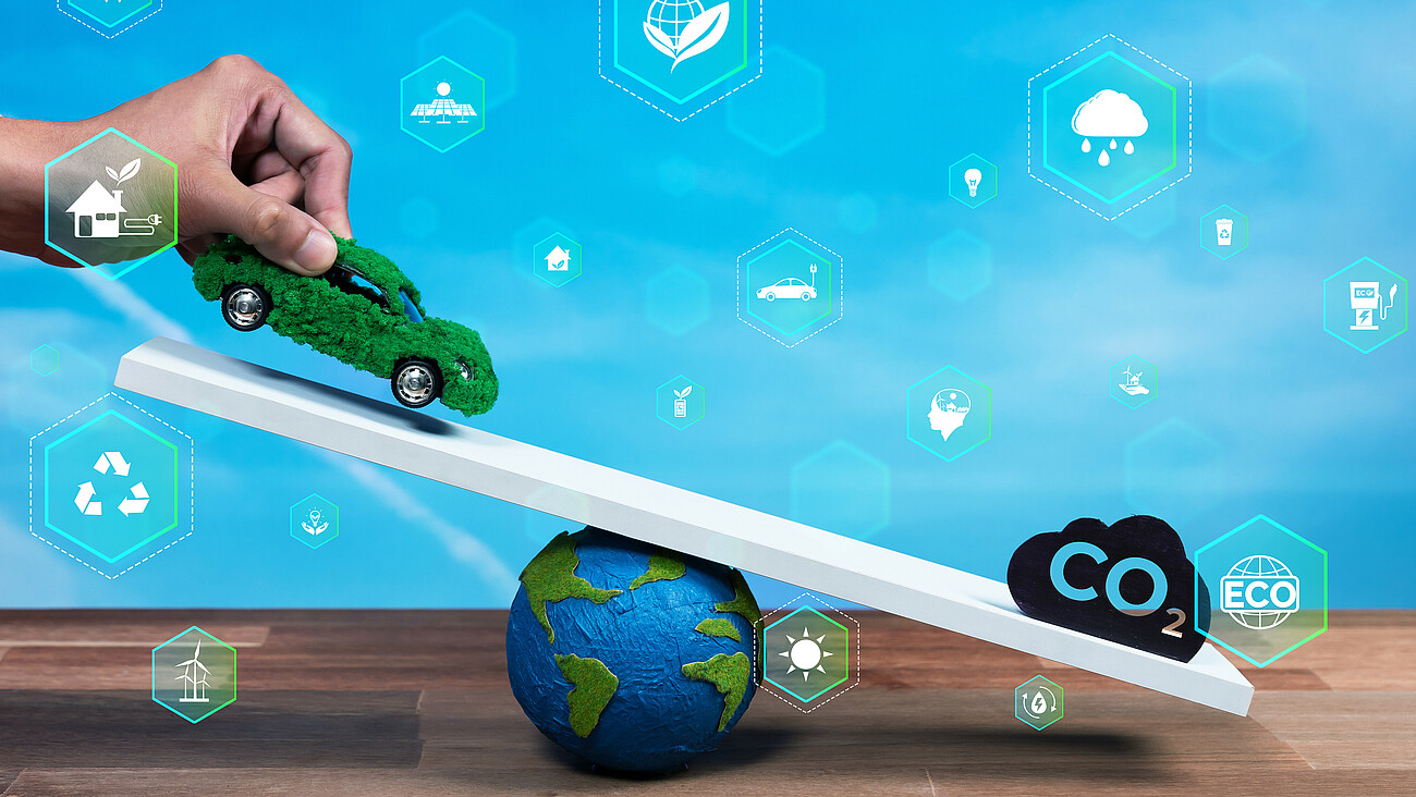 Businessman balance green EV car model scale with CO2 emission icon. Reliance